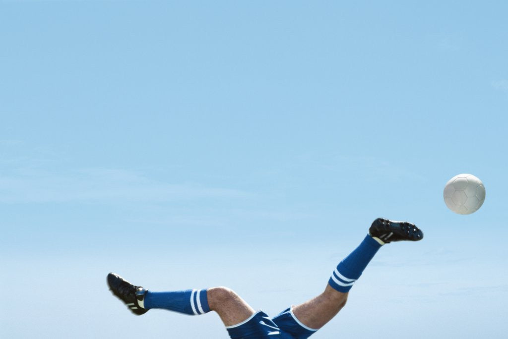 Detail of Soccer player upside-down attempting to kick the ball by Corbis