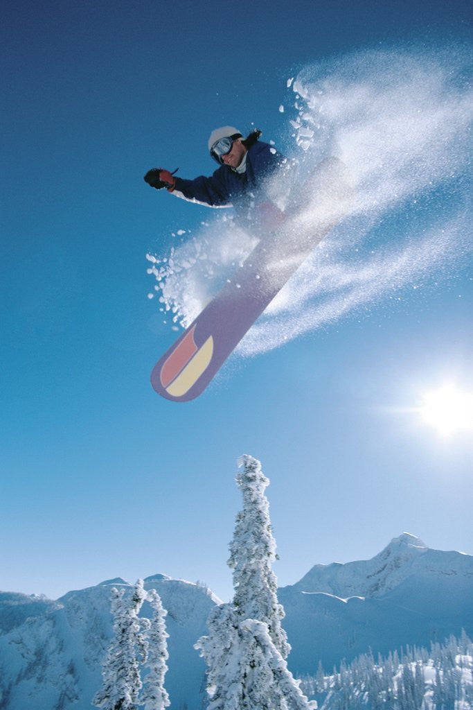 Detail of Man snowboarding on sunnny day by Corbis