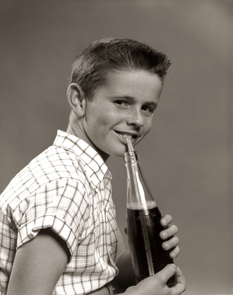 Detail of 1950s Boy Drinking Carbonated Beverage From Soda Pop Bottle With Straw by Corbis