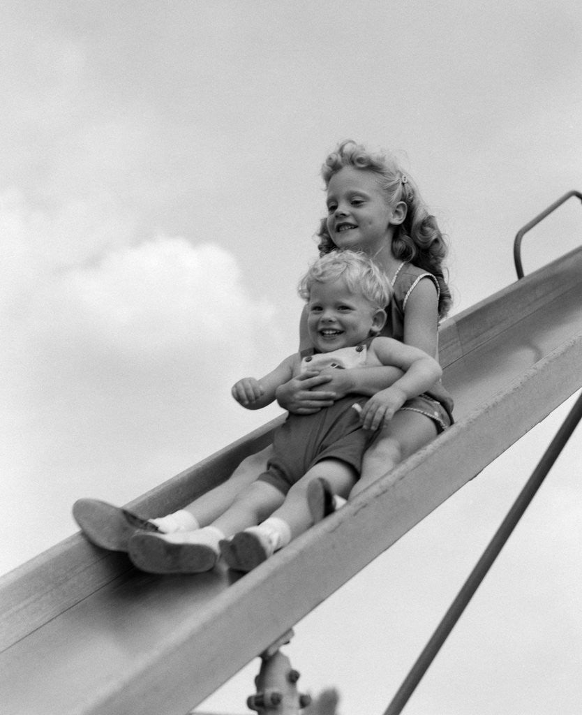 Detail of 1950s 1960s Two Children Going Down Playground Slide by Corbis