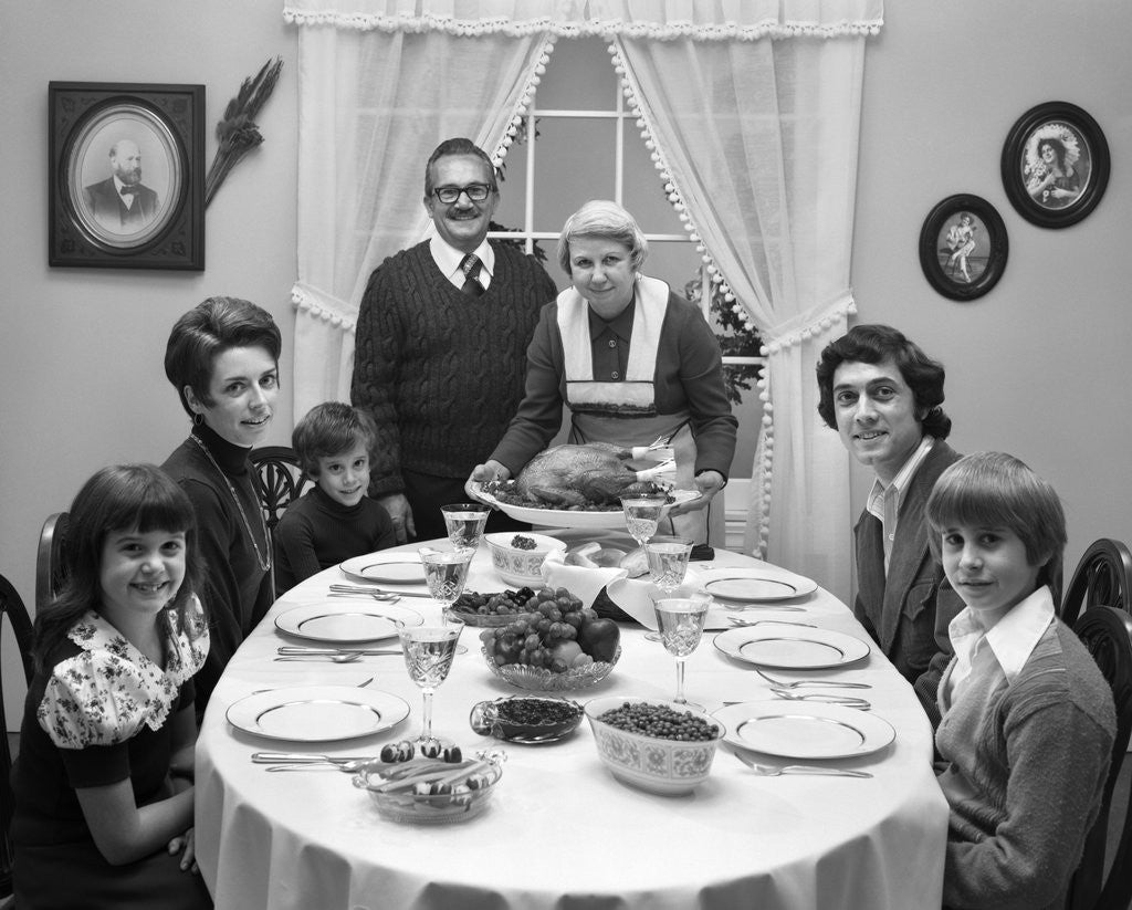 Detail of 1970s 3 Generation Family Sitting Dining Room Table Grandmother Setting Down Turkey Platter by Corbis