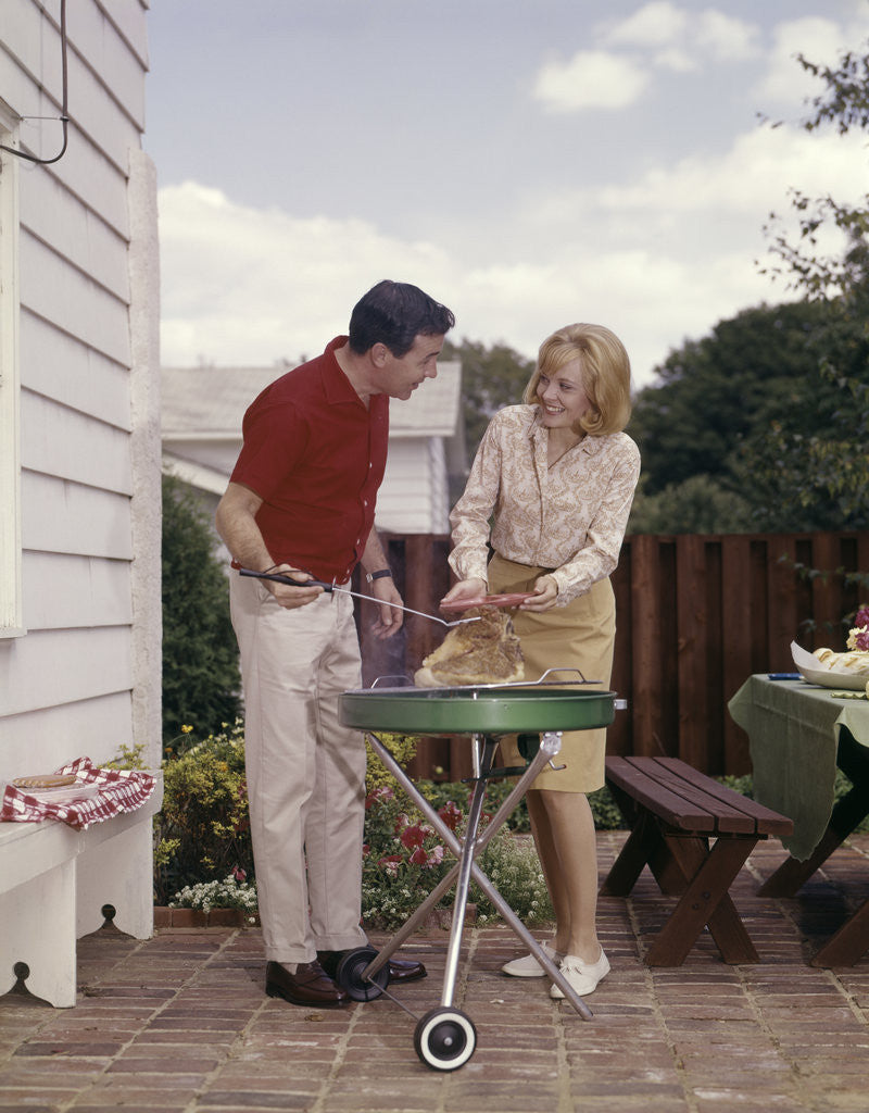 Detail of 1960s Couple Man Woman Grilling Steak On Backyard Patio Bar-B-Cue Charcoal Grill by Corbis