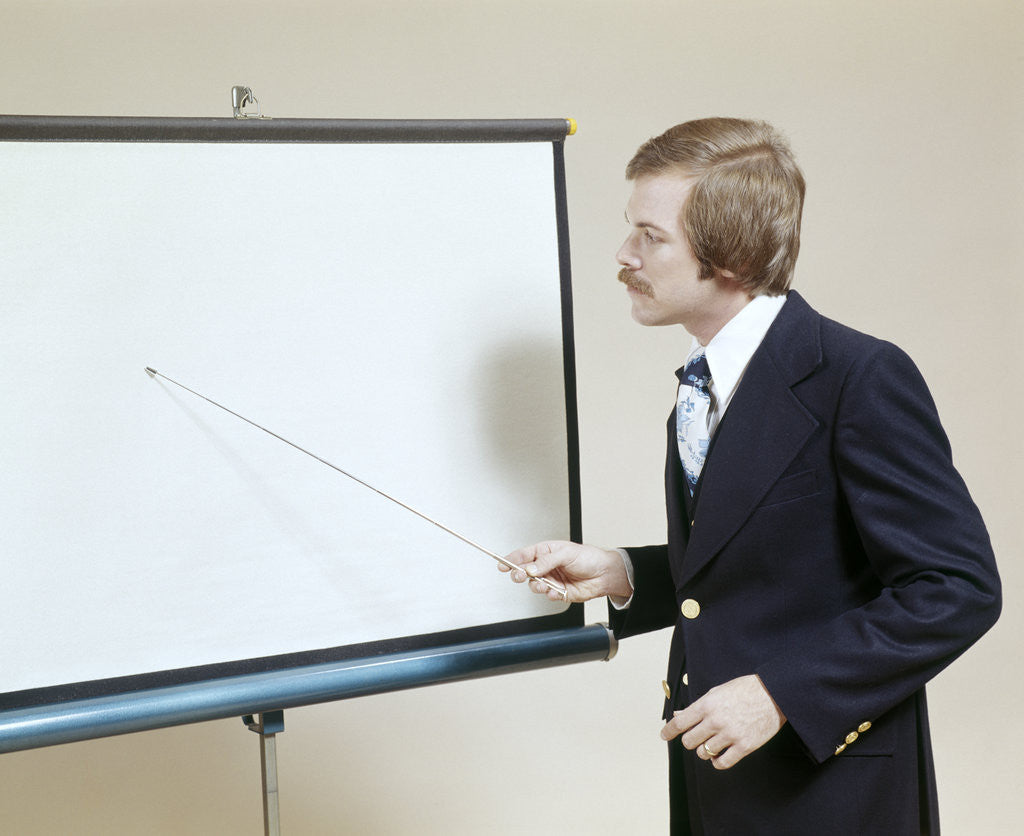 Detail of 1970s Business Man Giving Presentation Pointing At Projection Screen by Corbis