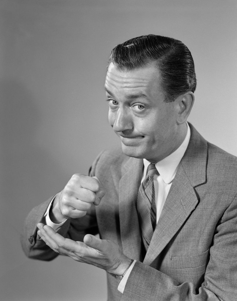 Detail of 1960s Man Determined Businessman Serious Expression Pounding Fist Into Palm Of His Hand by Corbis