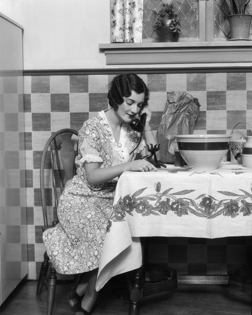 Detail of 1920s Woman Sitting At Kitchen Table With Table Cloth While On Phone by Corbis