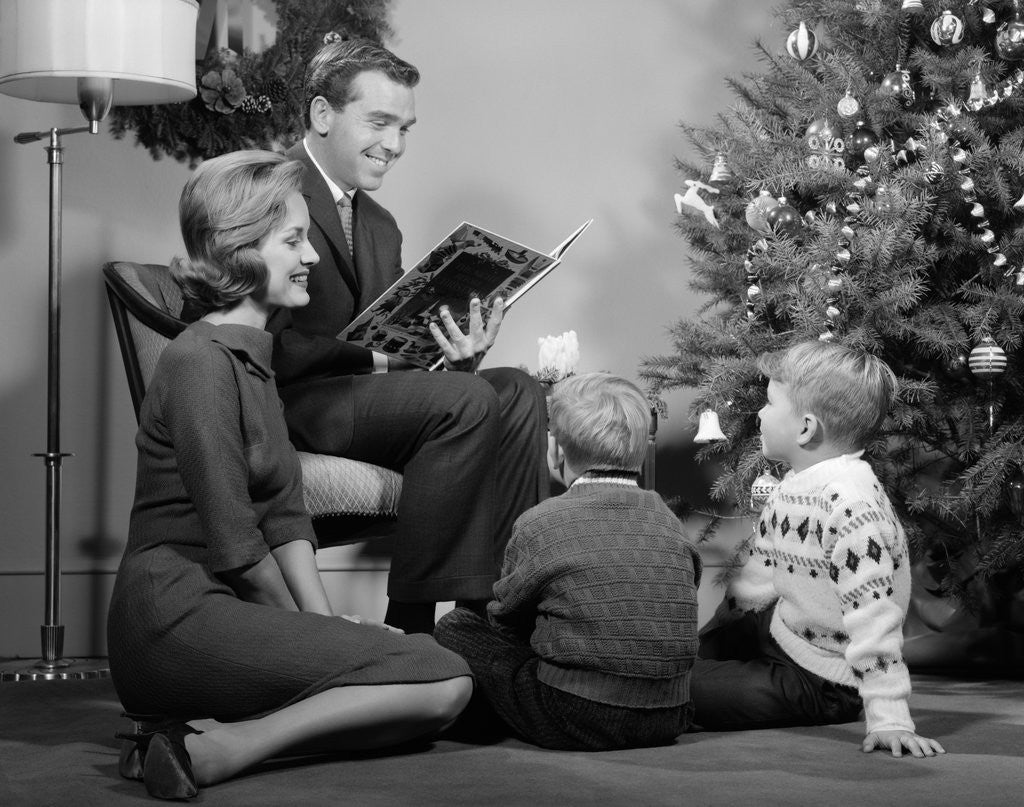 Detail of 1960s Family Father Mother Two Sons Sitting By Christmas Tree In Living Room Reading A Book by Corbis