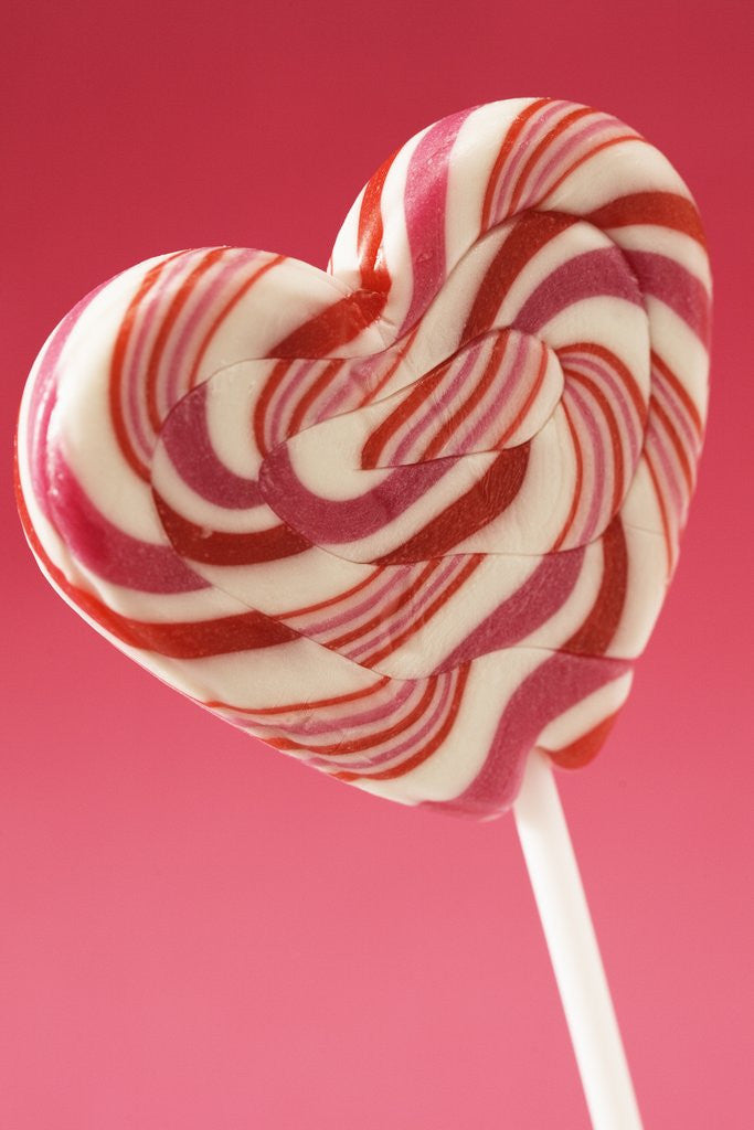 Detail of Red and white heart shaped lollipop against pink background, Close up by Corbis