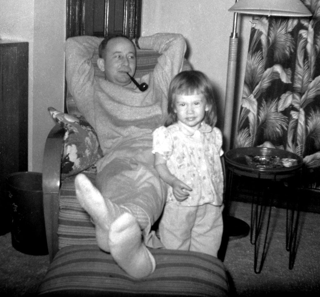 Detail of Dad relaxes and smokes his pipe with his four year old daughter, ca. 1958 by Corbis