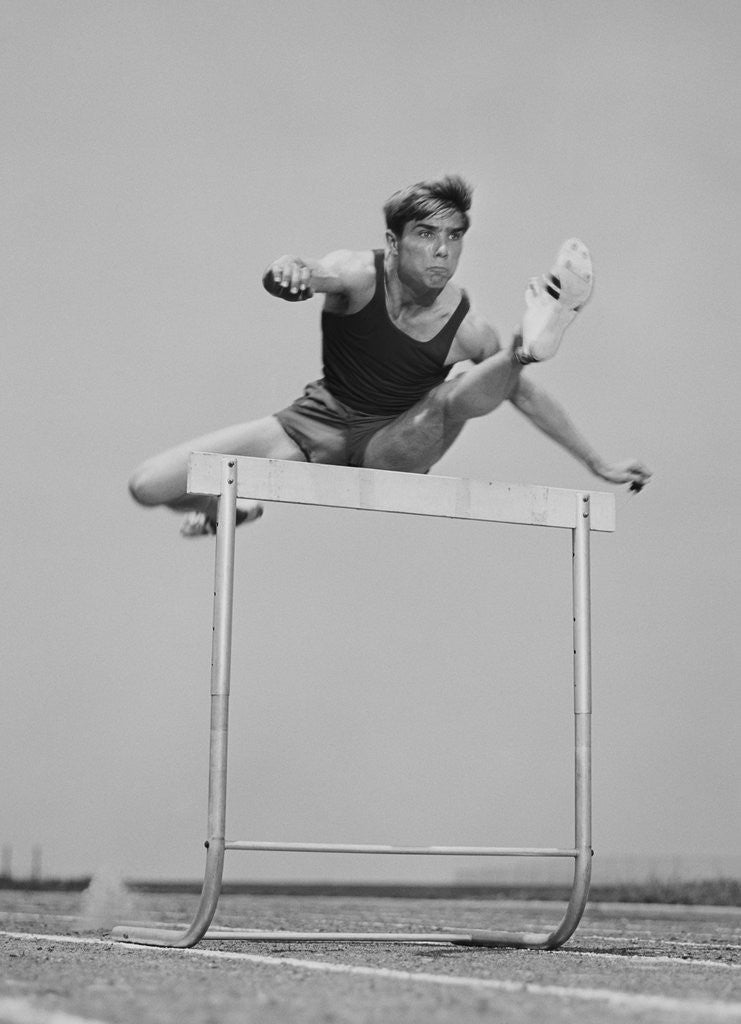 Detail of Running man jumping over hurdle by Corbis