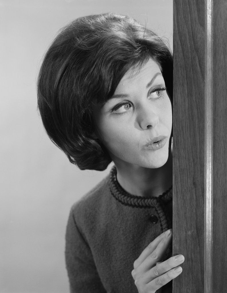 Detail of Brunette woman peeking around corner by Corbis