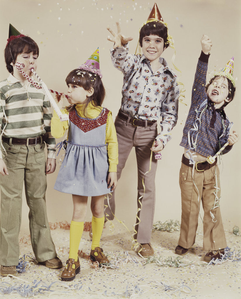 Detail of 4 kids wearing party hats tossing confetti by Corbis