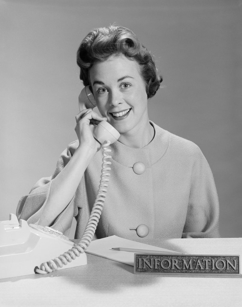 Detail of Smiling woman secretary talking on telephone information desk by Corbis