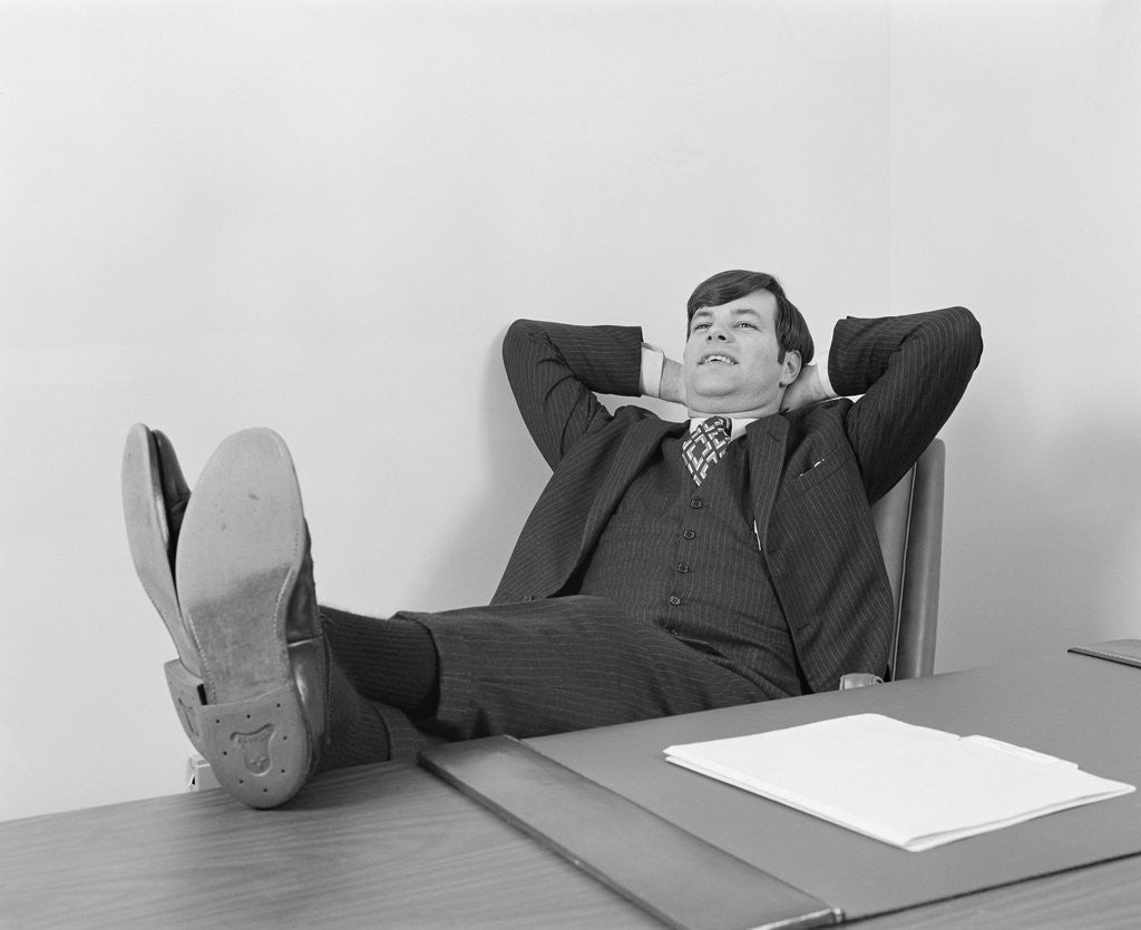 Detail of Confident young businessman sitting relaxed with feet up on desk by Corbis