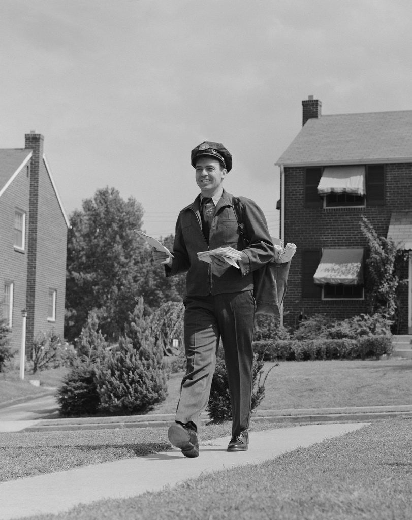 Detail of Postal mailman walking suburban street wearing uniform delivering mail by Corbis