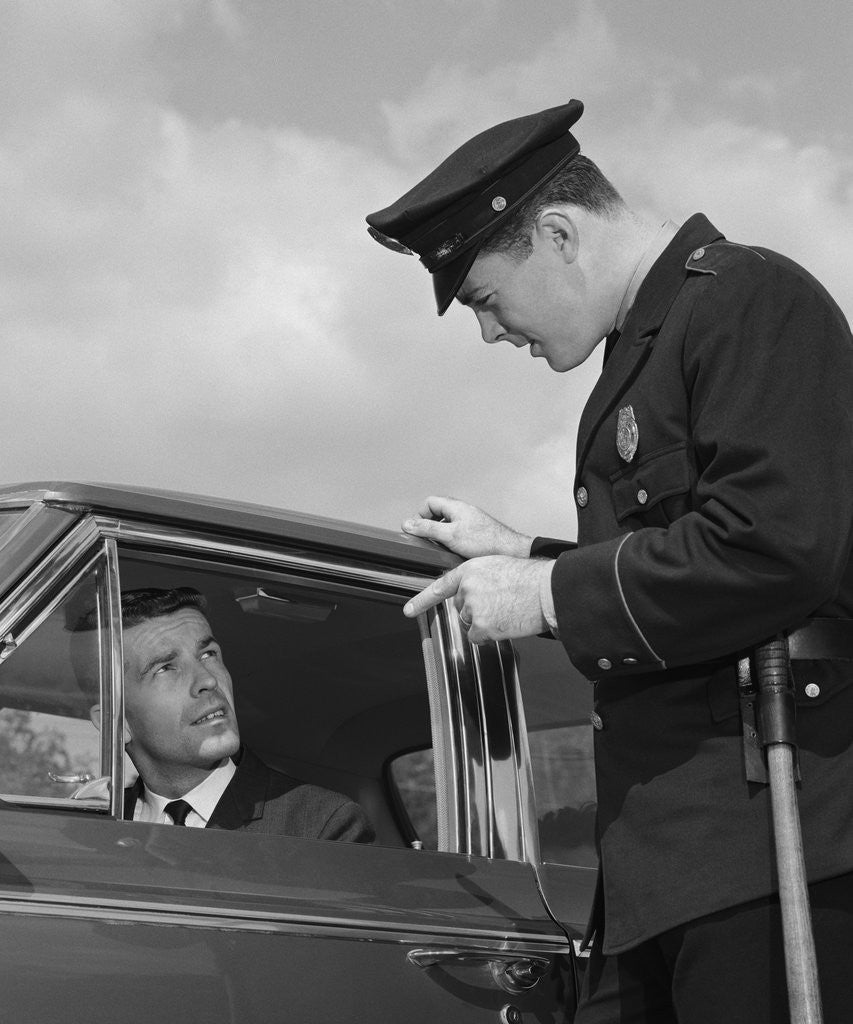 Detail of Police officer warning motorist pointing finger at driver by Corbis