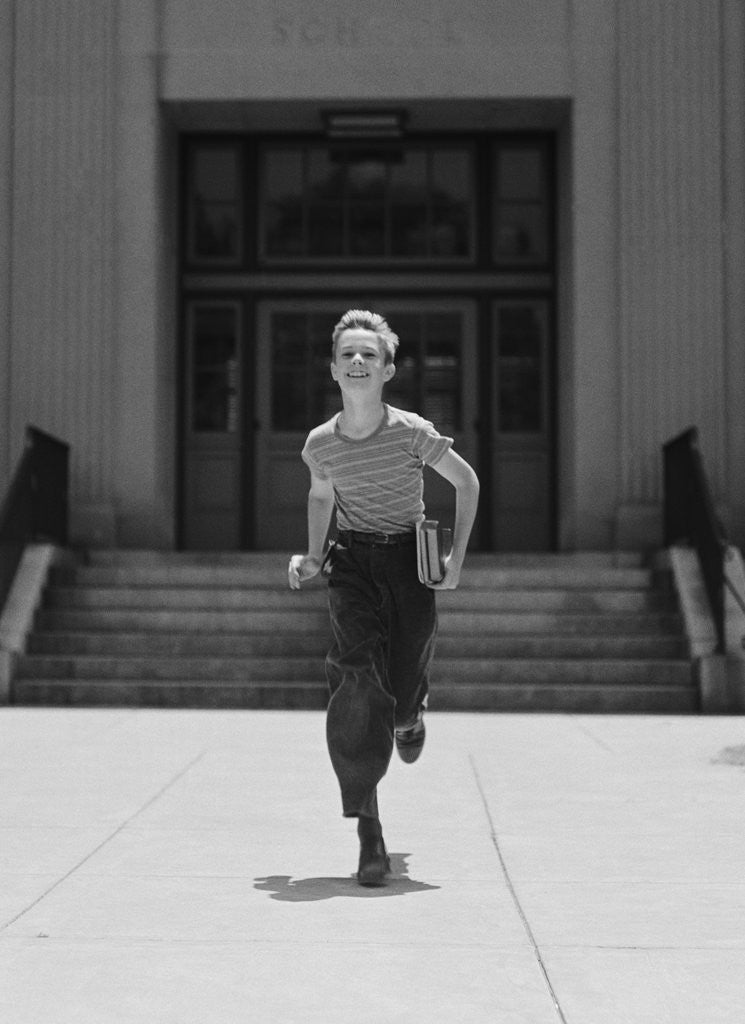 Detail of Boy running from school carrying books by Corbis