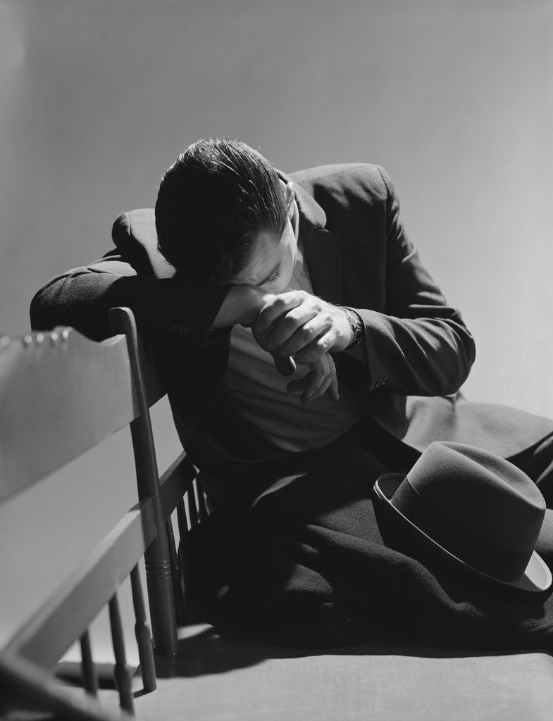 Detail of Businessman sitting on bench head down on arms slumped over sad depressed by Corbis