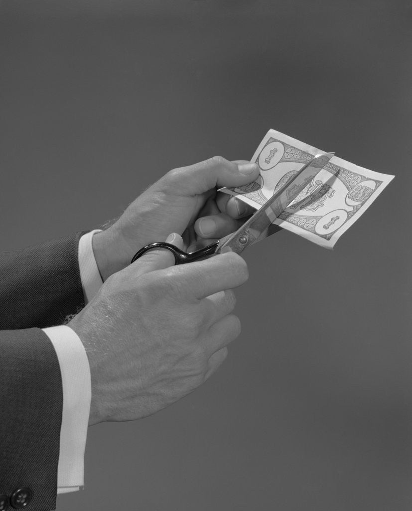 Detail of Male hands with scissors cutting dollar bill in half by Corbis