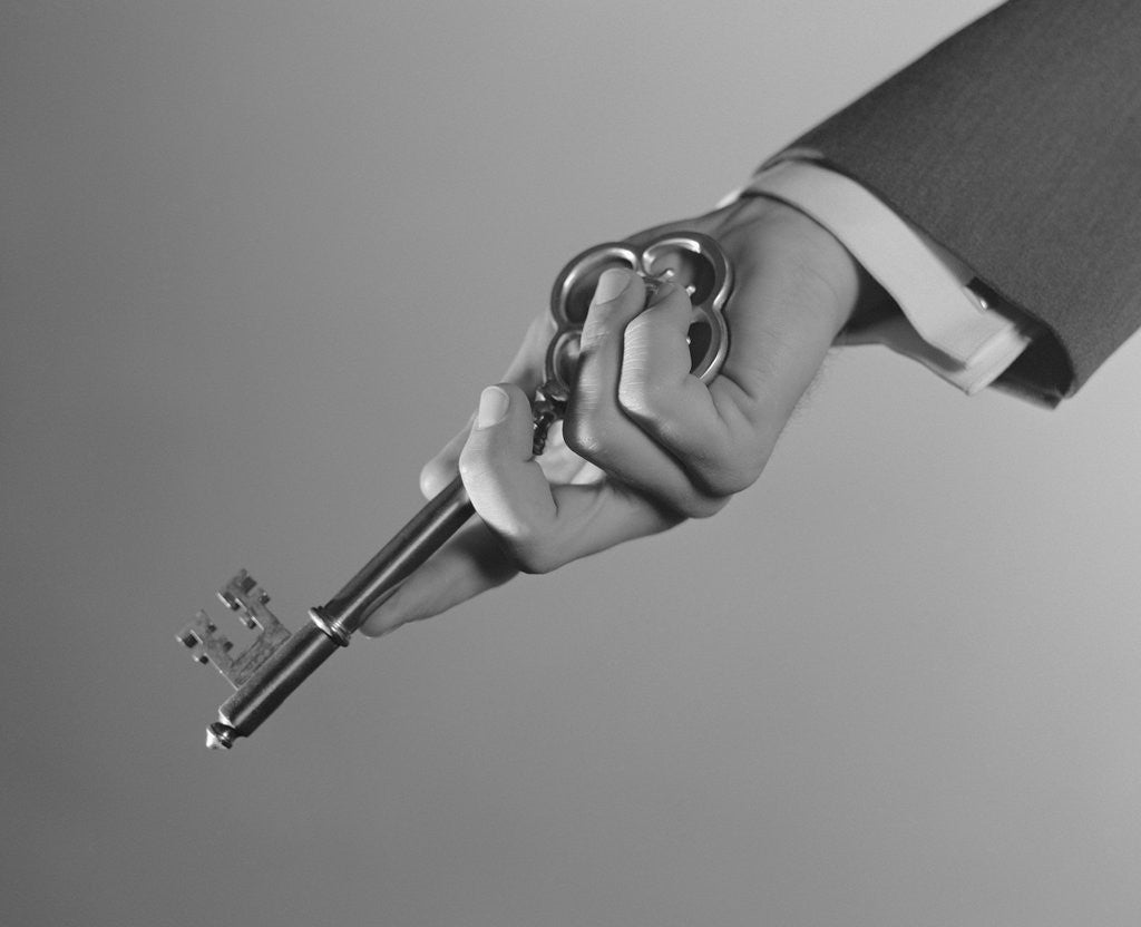 Detail of Male hand holding large key by Corbis