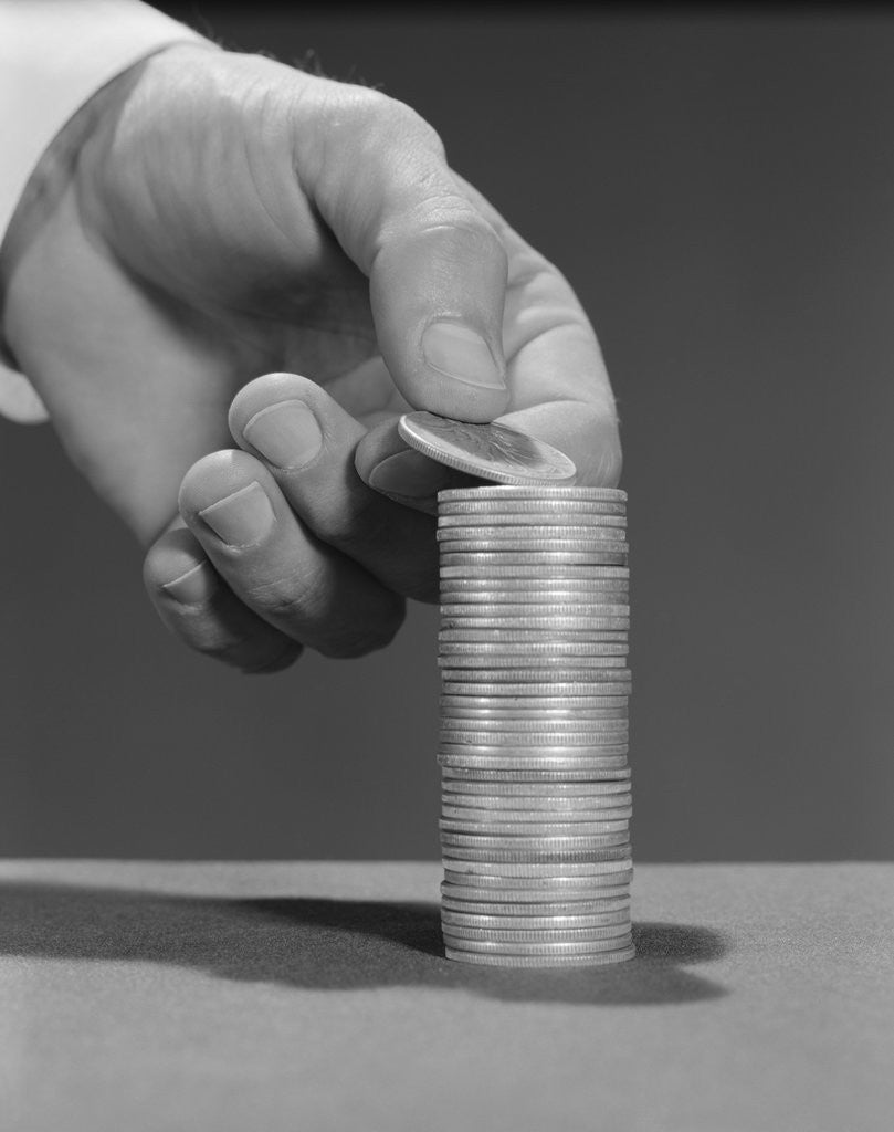 Detail of Male hand stacking coins money by Corbis