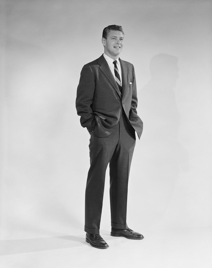 Detail of Portrait smiling man standing with hands in pockets wearing suit and tie by Corbis