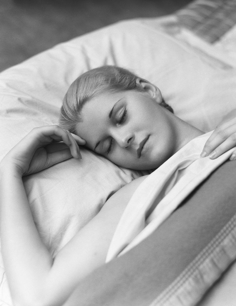 Detail of Sleeping blond woman eyes closed head resting on pillow in bed by Corbis