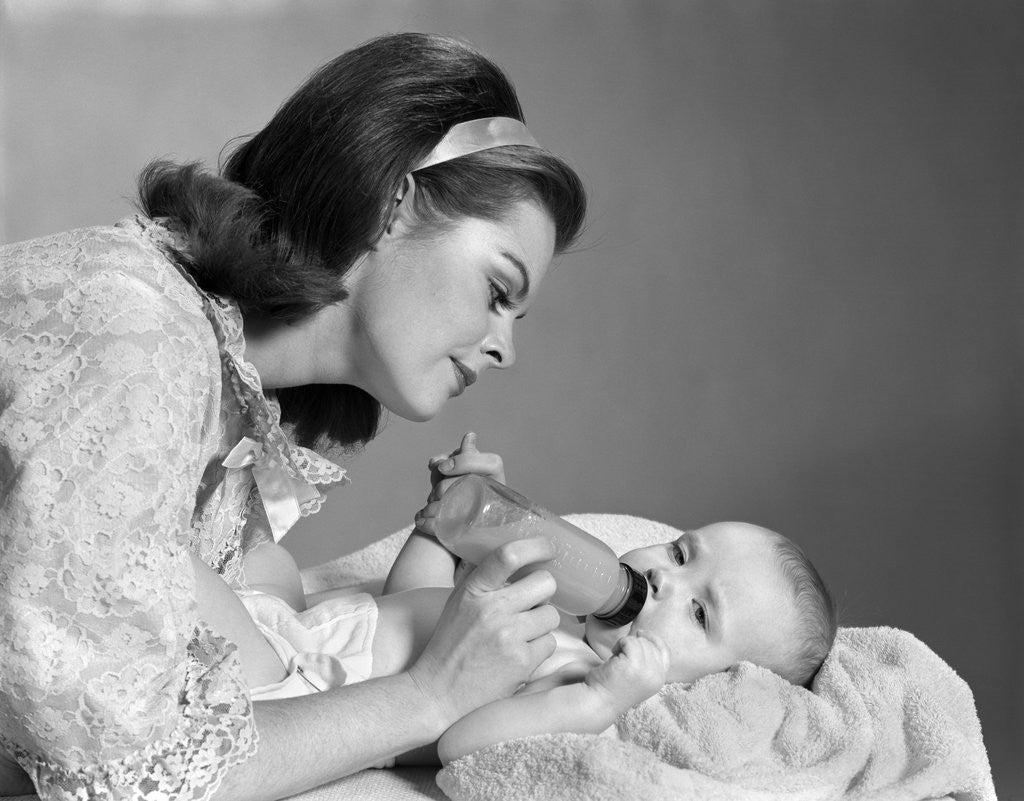 Detail of 1960s mother bottle feeding infant child by Corbis