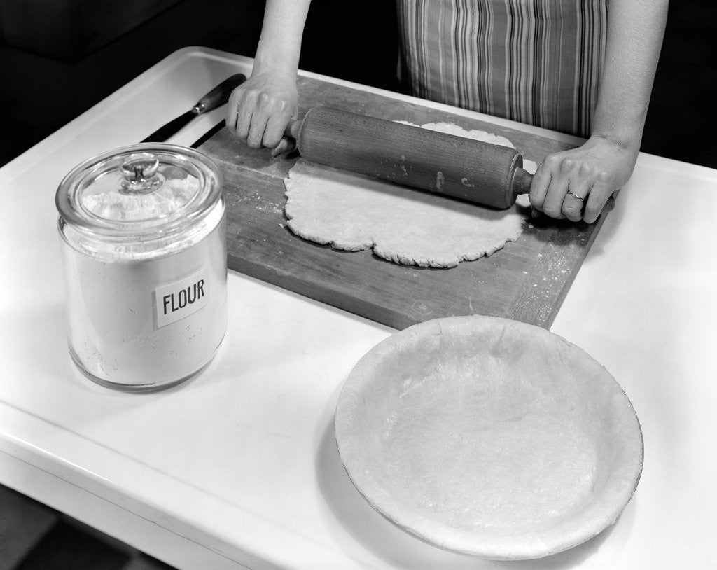 Detail of 1920s 1930s 1940s rolling pin flower apron hands baking pie by Corbis