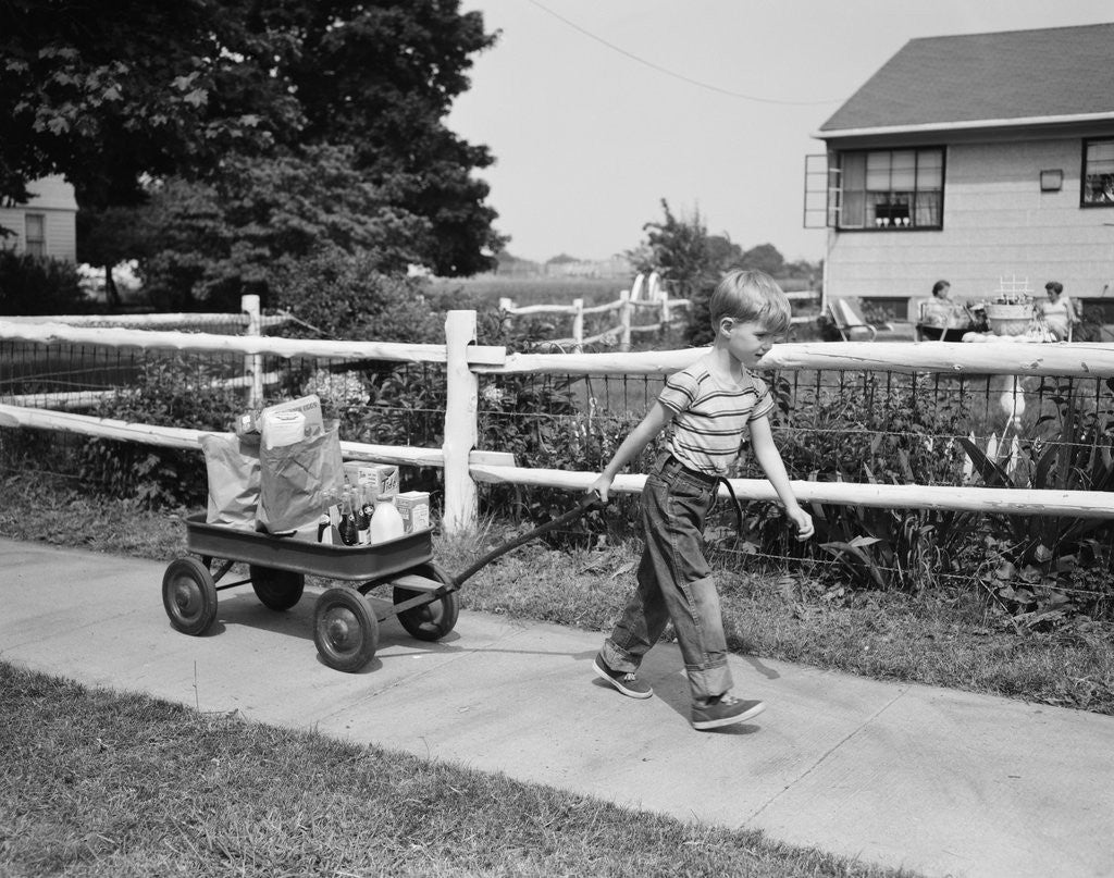 Detail of 1950s boy pulling groceries in wagon by Corbis