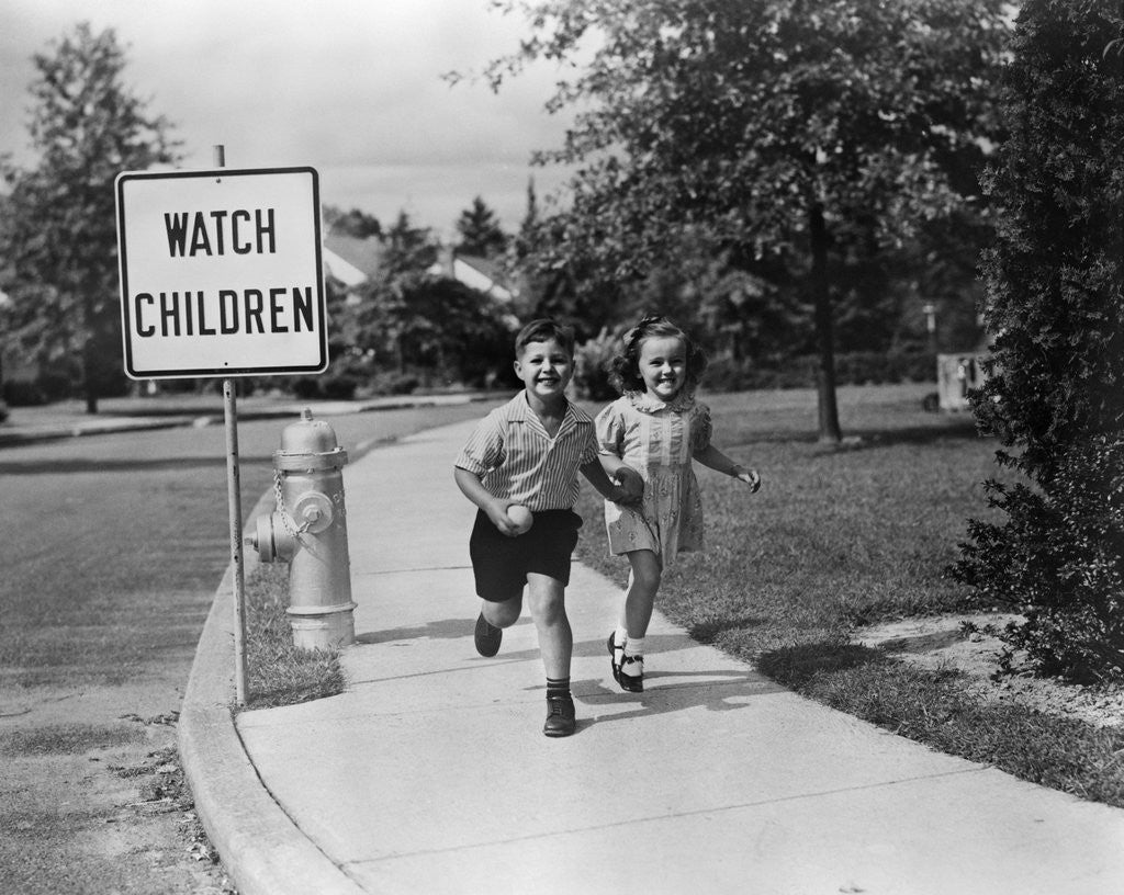 Detail of 1950s children skipping walking on sidewalk watch children sign by Corbis