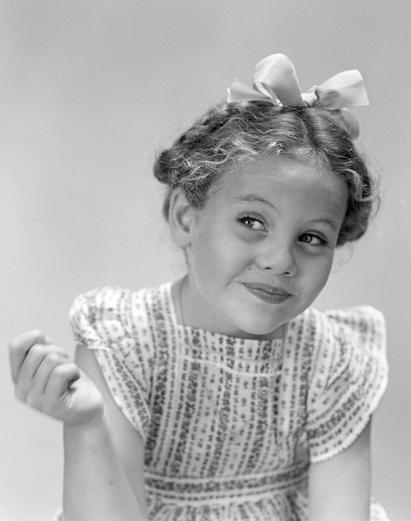 Detail of 1940s little girl smiling smirking looking off to one side by Corbis