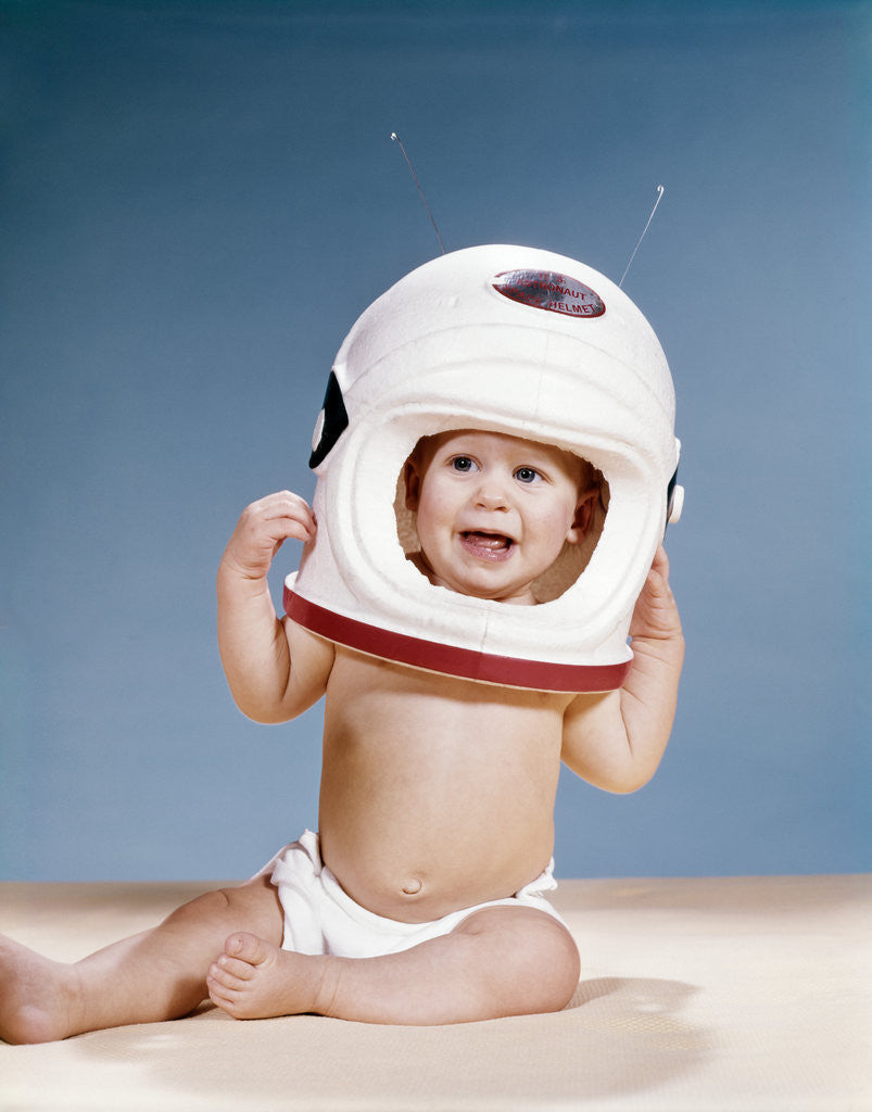 Detail of 1960s baby wearing styrofoam astronaut helmet by Corbis