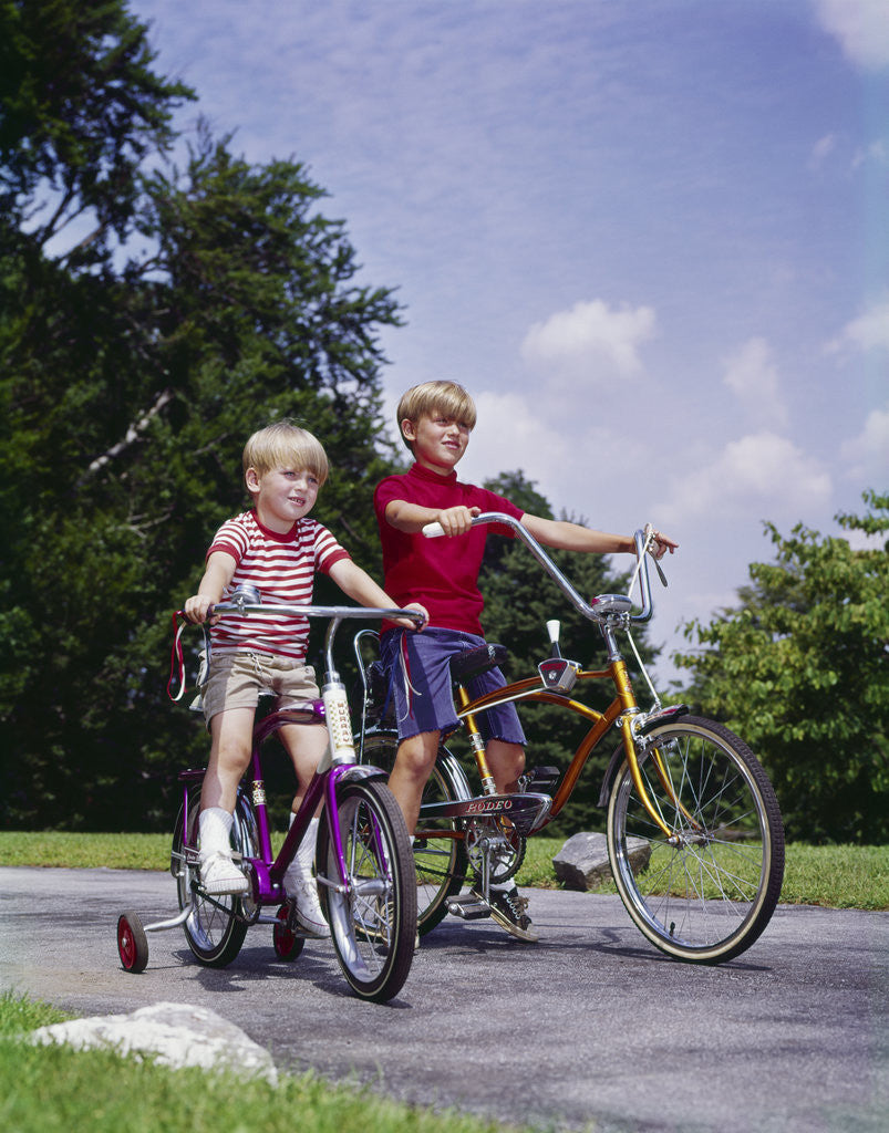 Detail of 1970s 1960s two boys riding bikes in park summer by Corbis