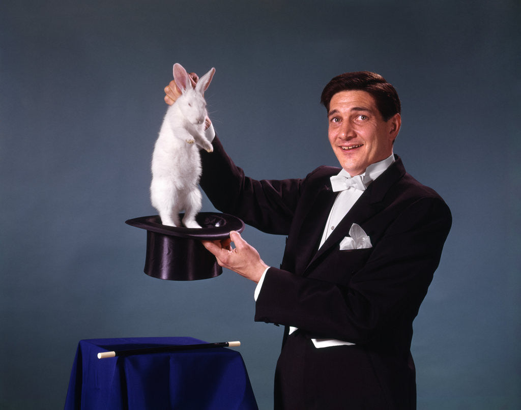 Detail of 1960s 1970s man magician tuxedo pulling rabbit out of top hat magic illusion sleight of hand trick by Corbis