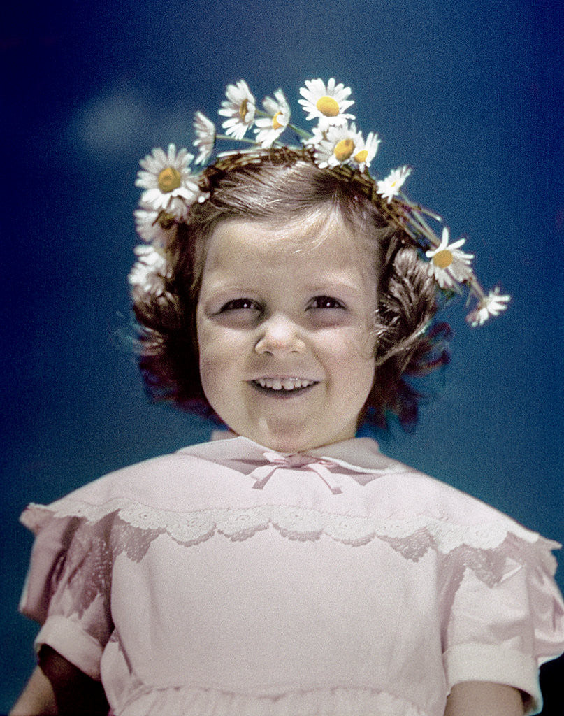 Detail of 1940s portrait smiling little girl wearing yellow and white crown of daisy flowers by Corbis