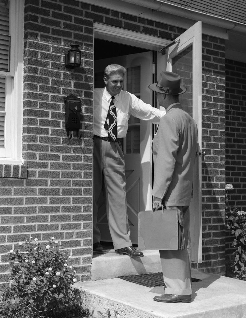 Detail of 1950s salesman talking to man at front door by Corbis