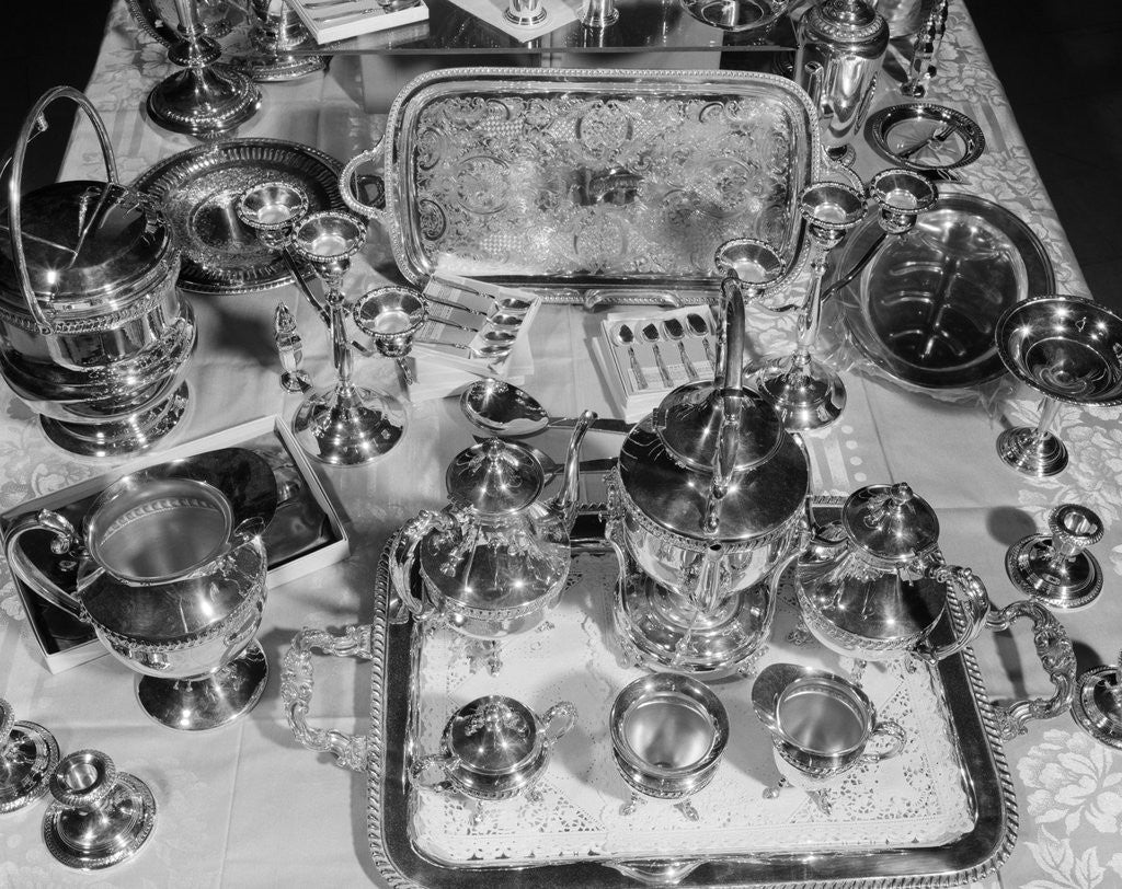 Detail of 1950s still life overhead view of assortment of silver service pieces including tea set candlesticks & ice bucket by Corbis