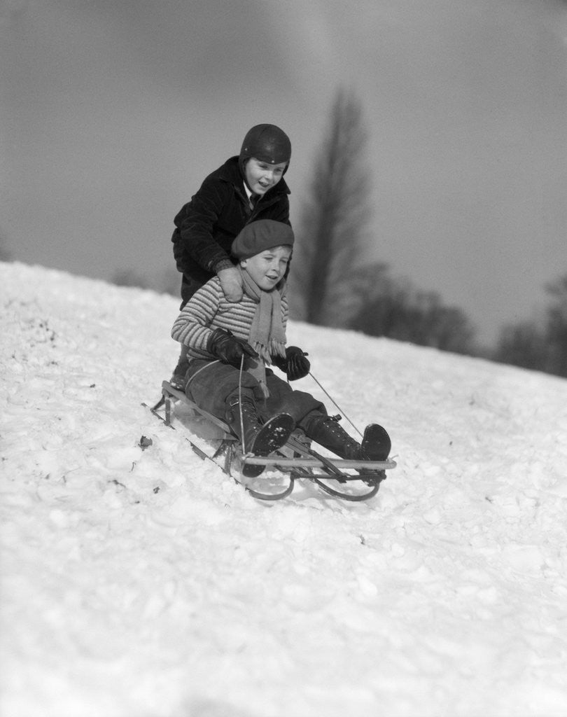 Detail of 1930s two boys sledding outside in snow by Corbis