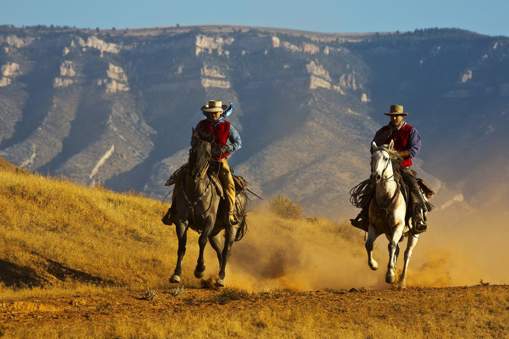 Detail of Cowgirl and cowboy riding together by Corbis