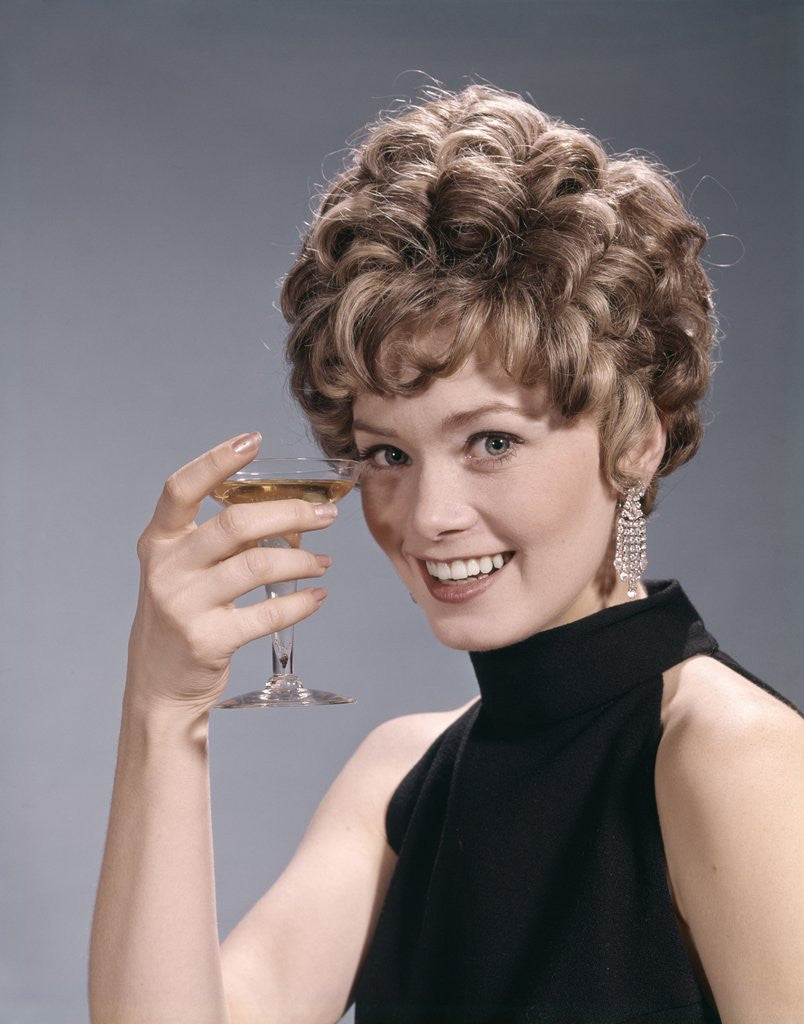 Detail of 1960s Portrait Glamourous Woman In Black Dress Earrings Holding A Cocktail Looking At Camera by Corbis