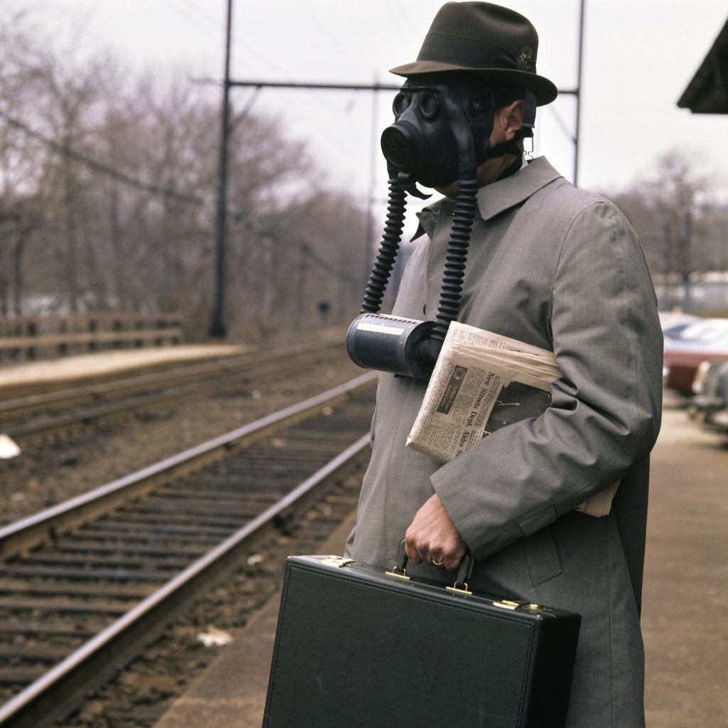 Detail of 1970s 1960s Man Commuter Waiting For Train Wearing Gas Mask Pollution by Corbis