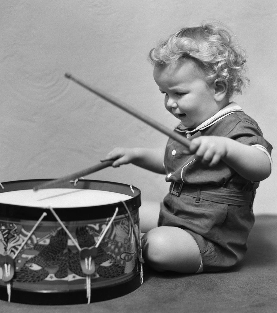 Detail of 1930s Toddler Boy Playing Toy Drum by Corbis
