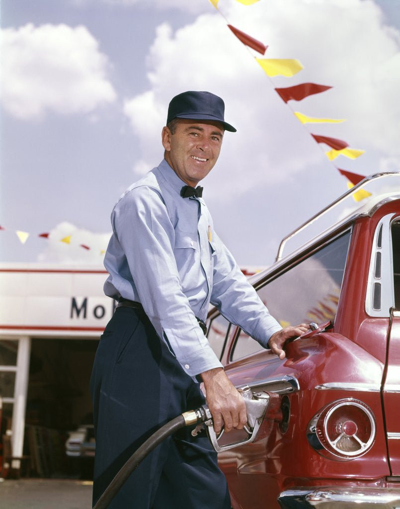 Detail of 1950s smiling service station attendant pumping gas by Corbis