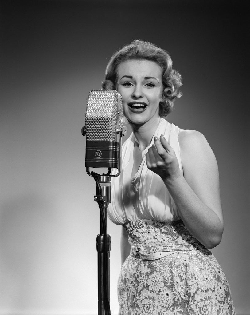 Detail of 1950s portrait of woman singing into a microphone by Corbis